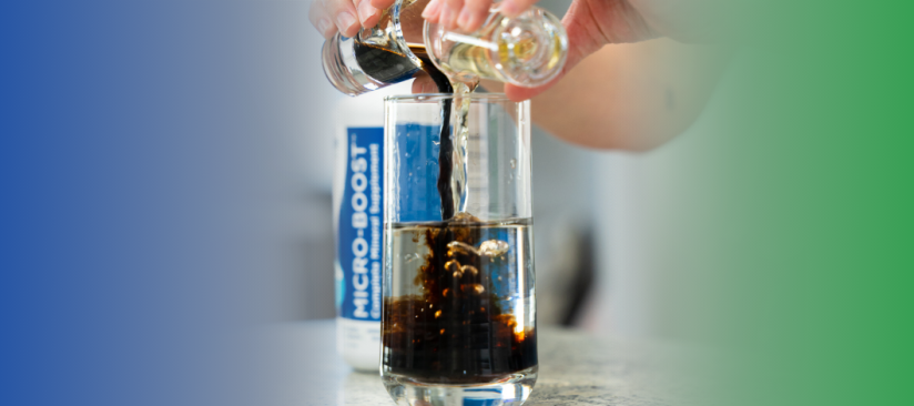 Woman pours two shot glasses of dark and clear liquid minerals into a glass of water, for a simple daily mineral supplement routine.